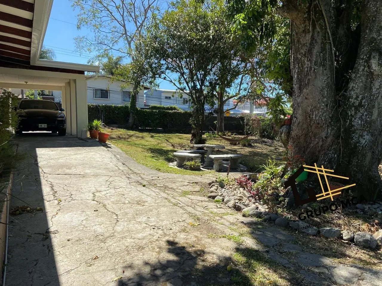 Cochera y jardín con árbol grande