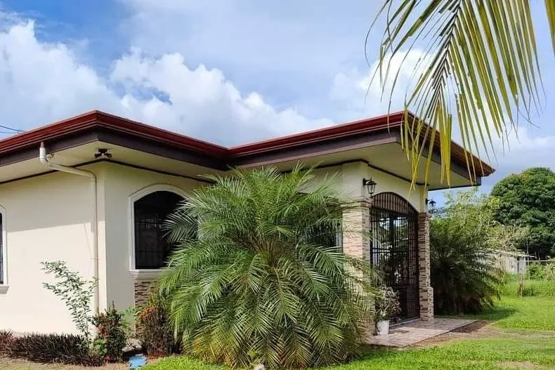Fachada de la casa con techo rojo y jardín