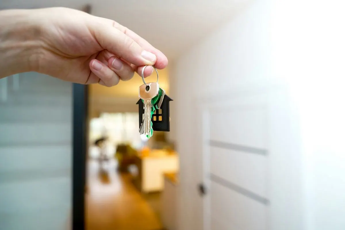Una mano entrega las llaves de una casa en la puerta