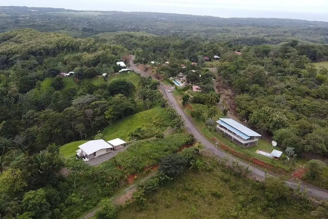 Toma aérea de un caserío entre fincas y bosque
